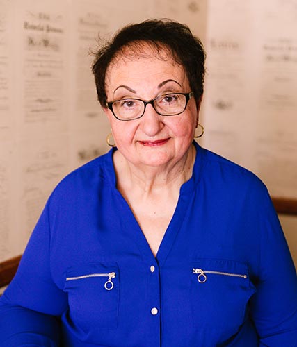 Victoria Sportelli smiles brightly at the camera, wearing a royal blue shirt.